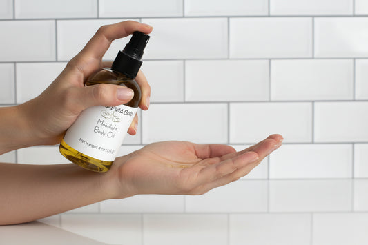 Hand holding a bottle of mandarin bath oil with a tiled bathroom background