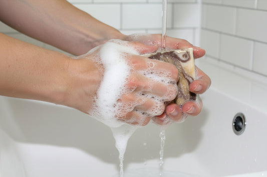 Person washing their hands with a bar of soap under running water in a sink.