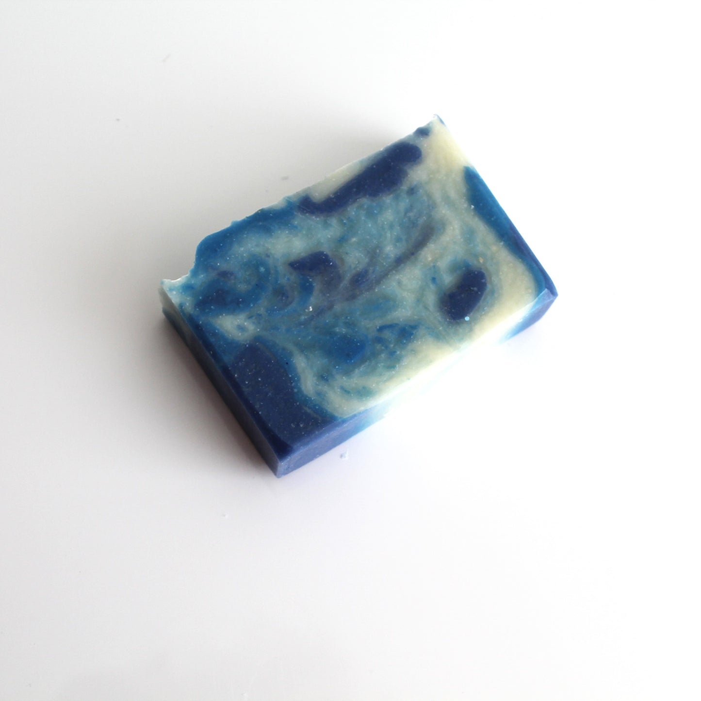 A bar of handcrafted Ocean Rain soap with a blue and white marbled pattern, placed on a white background.